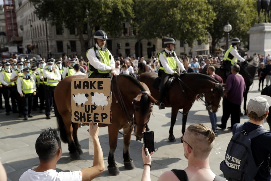 A protester holds up a placard in front of police officers during a &quot;Resist and Act for Freedom&quot; protest against a mandatory coronavirus vaccine, wearing masks, social distancing and a second lockdown, in Trafalgar Square, London, Saturday, Sept. 19, 2020.