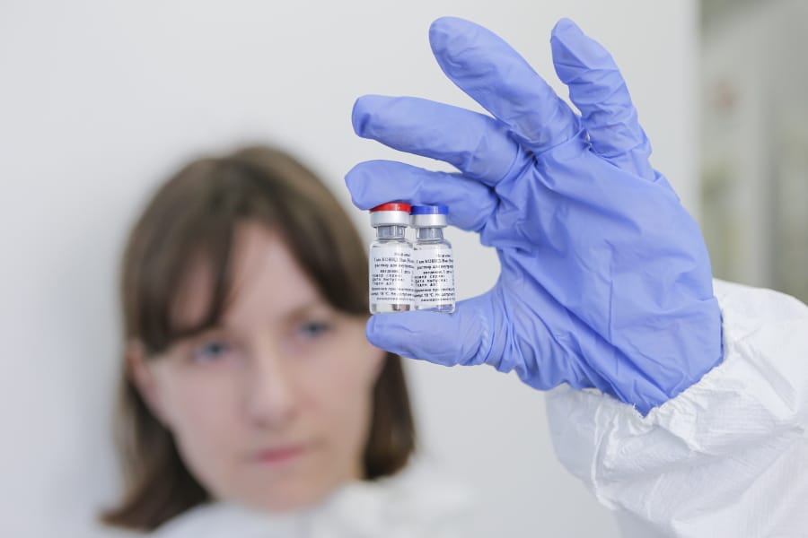 In this handout photo taken on Thursday, Aug. 6, 2020, and provided by Russian Direct Investment Fund, an employee shows a new vaccine at the Nikolai Gamaleya National Center of Epidemiology and Microbiology in Moscow, Russia.