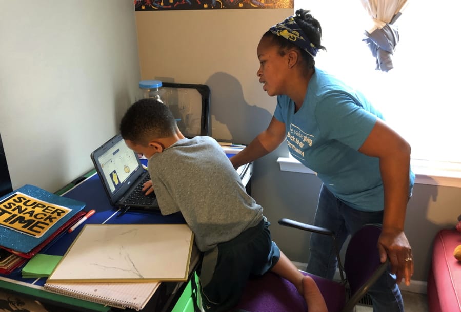 Tiffany Shelton helps her 7-year-old son, P.J. Shelton, a second-grader, during an online class at their home in Norristown, Pa., on Thursday, Sept. 3, 2020. Norristown Area School District plans to offer online-only instruction through at least January 2021.
