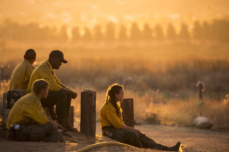 Firefighters rest during a wildfire in Yucaipa, Calif., Saturday, Sept. 5, 2020. Firefighters trying to contain the massive wildfires in Oregon, California and Washington state are constantly on the verge of exhaustion as they try to save suburban houses, including some in their own neighborhoods. (AP Photo/Ringo H.W.