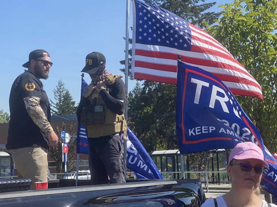 Men wearing symbols of Proud Boys, a violent right-wing extremist group, stand watch as supporters of President Donald Trump kick off a truck caravan near Portland, Oregon.