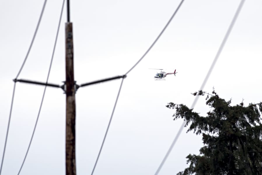 Clark Public Utilities staff ride in a helicopter to inspect vegetation around a transmission line in northwestern Camas. The utility provider is hoping that adding helicopter and drone flights will allow it to be more proactive in monitoring vegetation and making sure its power lines stay clear.