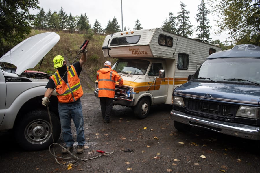 City workers help a woman jump-start her RV at Leverich Park in Vancouver on Tuesday. The city gave people staying at the park help with gasoline, jump-starts and offered them a tow to the Safe Park Zone at Evergreen Transit Center.