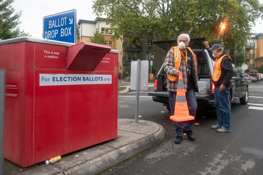 Elections workers John Waterbury, left, and Les Stark set up a safety cone before collecting ballots from an official drop box near the Clark County Elections Office on Saturday morning, October 17, 2020.
