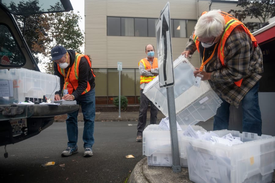 Elections worker John Waterbury, right, collects ballots from an official drop box near the Clark County Elections Office as Clark County Auditor Greg Kimsey, center, looks on, and elections worker Les Stark makes notes on October 17, 2020, in downtown Vancouver.