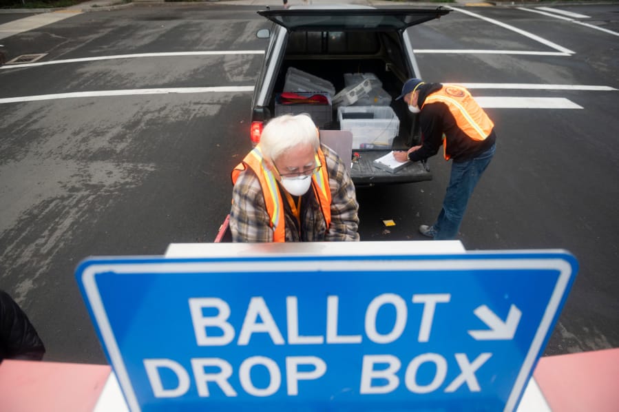 Elections workers John Waterbury, left, and Les Stark collect ballots from an official drop box near the Clark County Elections Office on Saturday morning, October 17, 2020.
