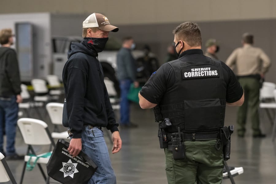Zach Nygaard, left, speaks with a deputy in a socially distanced seating area during a recruitment event for Clark County Jail corrections deputies Tuesday evening at the Clark County Event Center at the Fairgrounds.