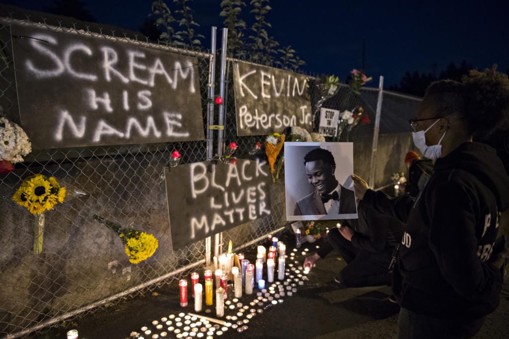 Alisha, one of the event organizers who declined to give her last name, holds a photo of Kevin Peterson Jr., a 21-year-old Black Camas man who was killed Thursday, as he is remembered with a candlelight vigil at the Hazel Dell branch of U.S. Bank on Friday night, Oct. 30, 2020.