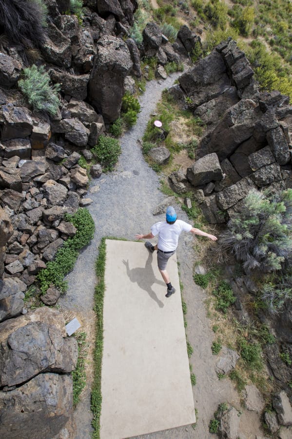 Nate Anderson of Bend throws his disk through a tight rock outcropping at the seventh hole tee box during a round of disk golf at Pine Nursery Park this summer.