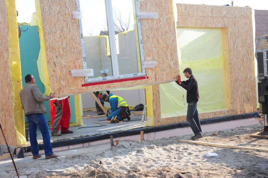 Contractors install modular frame plywood board panel walls house on the home construction site in 2018 in Kyiv, Ukraine. Oriented Strand Board now fetches a higher price as increased demand and tight supplies lead to delivery delays and elevated construction costs in the U.S. and Canada.