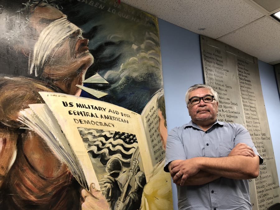 Immigrant rights activist Salvador Sanabria stands beside a mural dedicated to the victims of the civil war in El Salvador. He recalls the election disruption in the 1970s that set the stage for the 12-year conflict.
