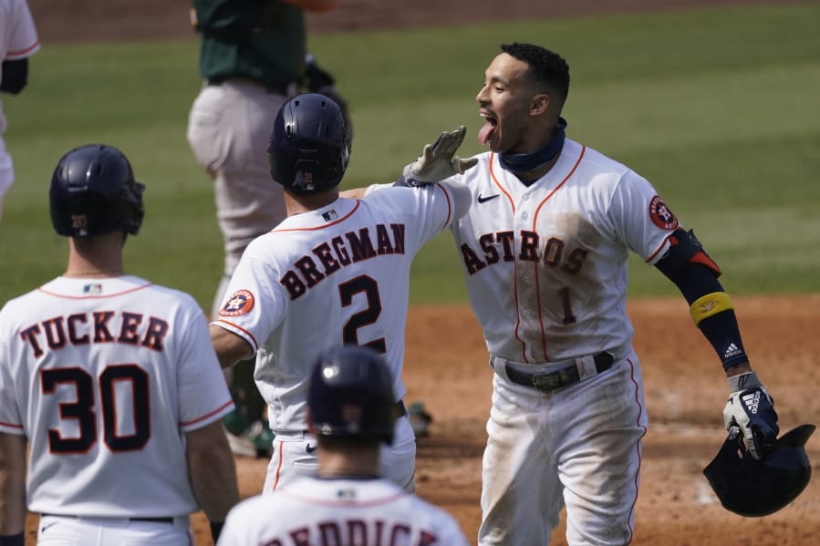 Houston Astros&#039; Carlos Correa, right, celebrates after hitting a three-run home run that scored Kyle Tucker (30) and Alex Bregman (2) during the fourth inning of Game 4 of a baseball American League Division Series against the Oakland Athletics in Los Angeles, Thursday, Oct. 8, 2020.