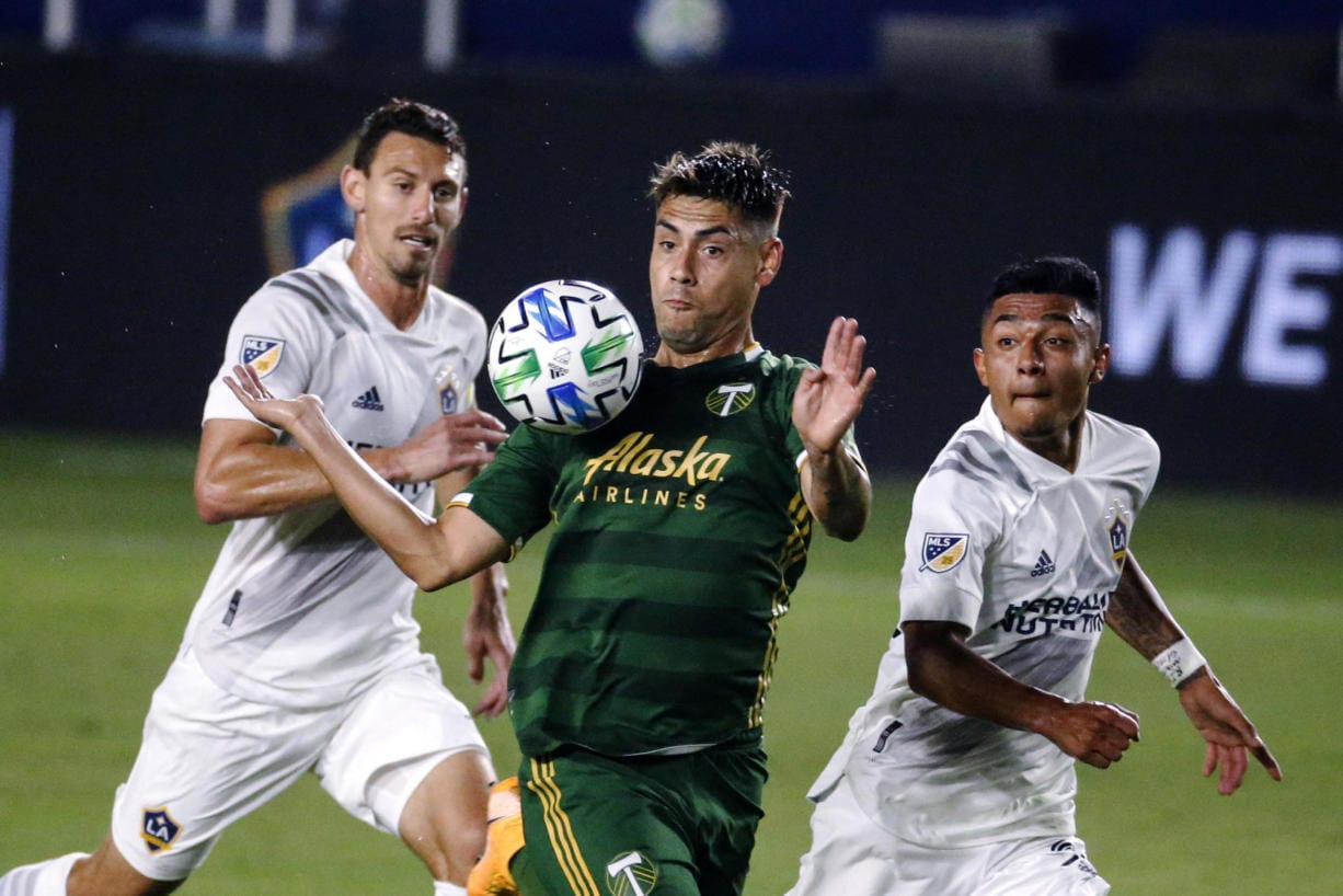 Portland Timbers forward Felipe Mora, center, controls the ball near two LA Galaxy players, including Sacha Kljestan, left, during the first half of an MLS soccer match in Carson, Calif., Wednesday, Oct. 7, 2020. (AP Photo/Ringo H.W.