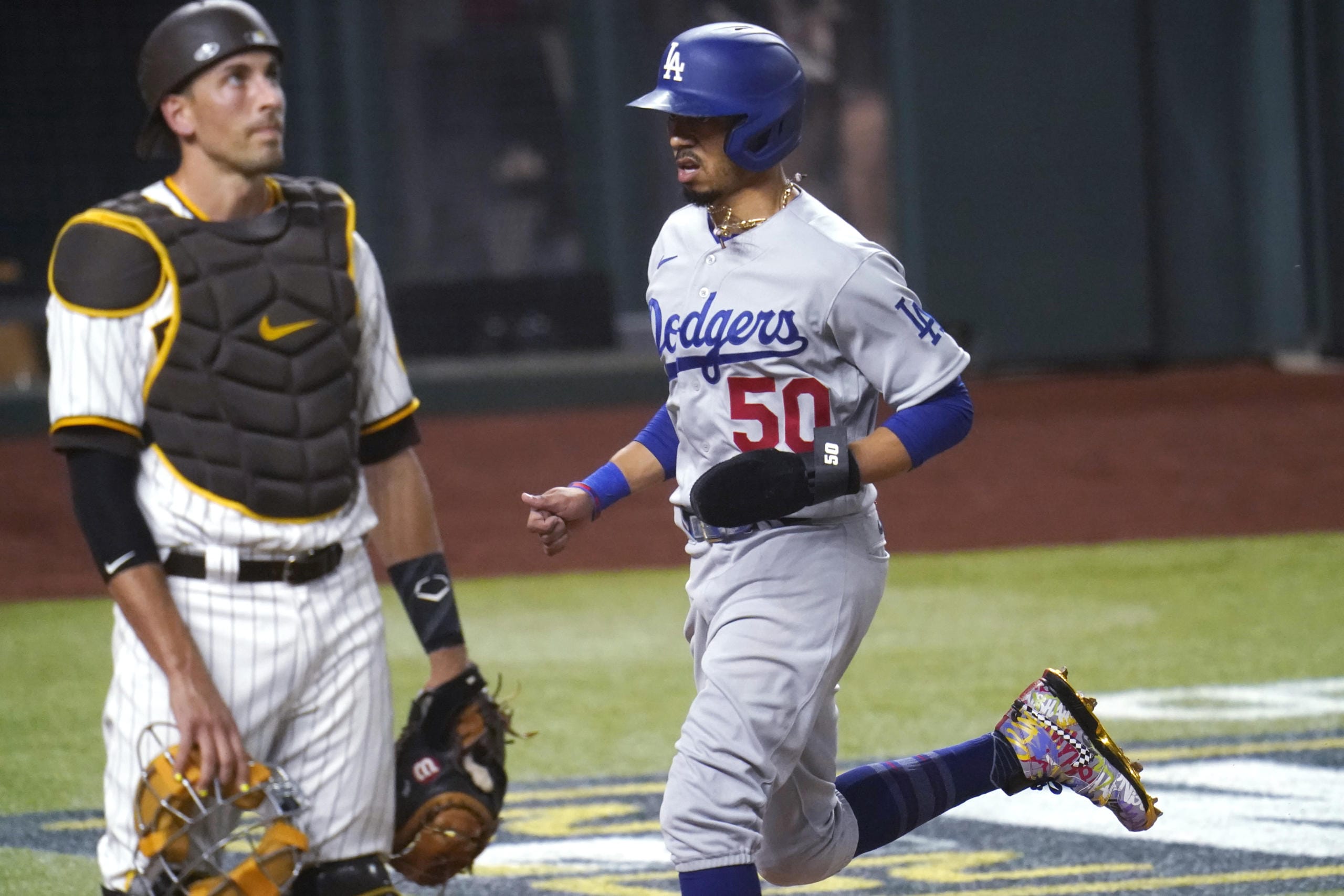 Los Angeles Dodgers' Mookie Betts (50) scores on a throwing error by San Diego Padres' Fernando Tatis Jr. during the third inning in Game 3 of a baseball National League Division Series Thursday, Oct. 8, 2020, in Arlington, Texas. At left is San Diego Padres catcher Jason Castro.
