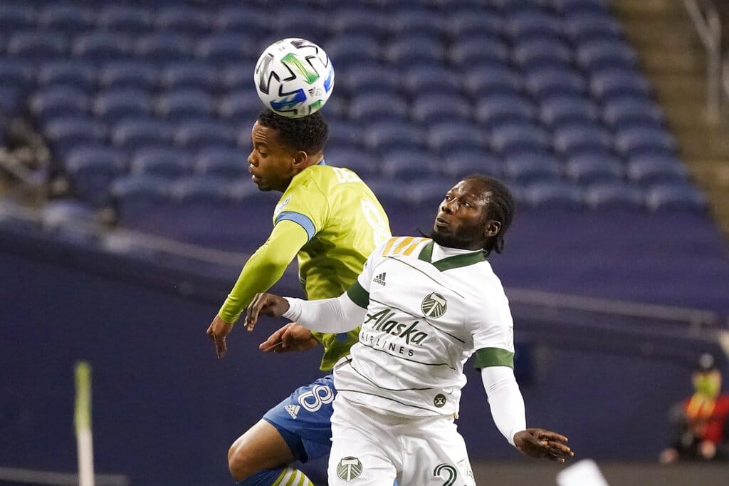Seattle Sounders' Jordy Delem (8) heads the ball in front of Portland Timbers' Yimmi Chara in the first half of an MLS soccer match, Thursday, Oct. 22, 2020, in Seattle.