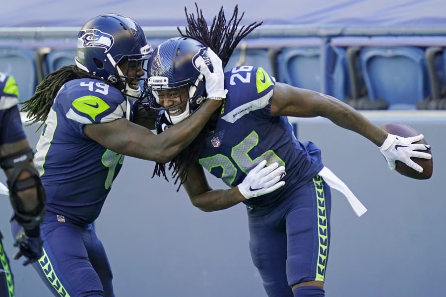 Seattle Seahawks cornerback Shaquill Griffin (26) is greeted by his twin brother, outside linebacker Shaquem Griffin (49), after Shaquill Griffin intercepted a pass against the Dallas Cowboys during the first half of an NFL football game, Sunday, Sept. 27, 2020, in Seattle.