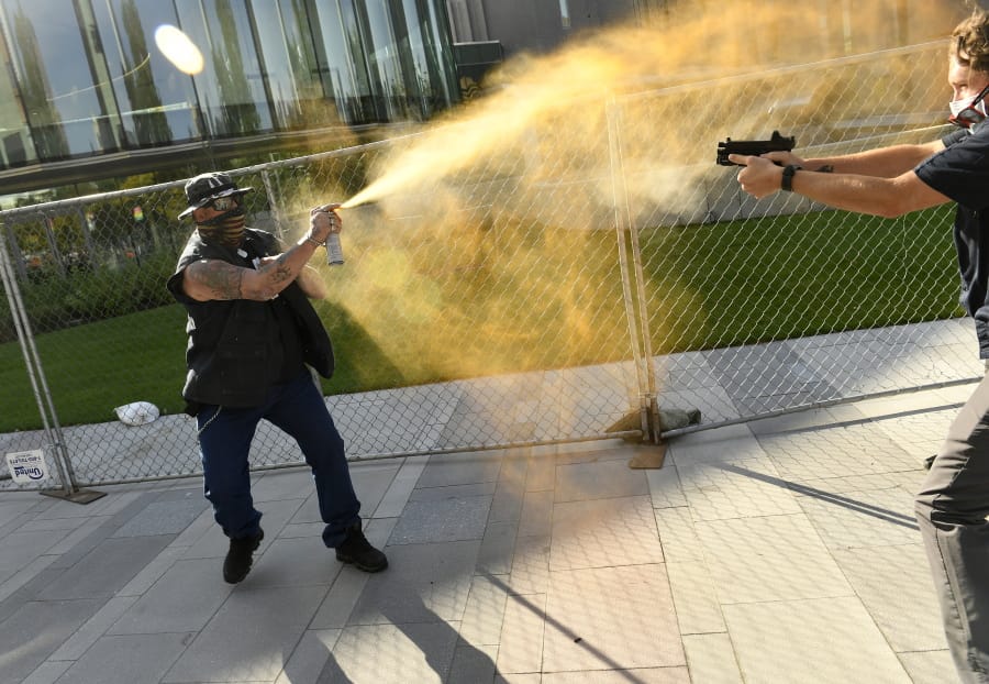 A man sprays mace, left, as another man fatally fires a gun, Saturday, Oct. 10, 2020 in Denver. The man on the left side of the photo was supporting the &quot;Patriot Rally&quot; and sprayed mace at the man on the right side of the image. The man at right, then shot and killed the protester at left. A private security guard working for a TV station was in custody Saturday after a person died from a shooting that took place during dueling protests in downtown Denver, the Denver Post reported. (Helen H.