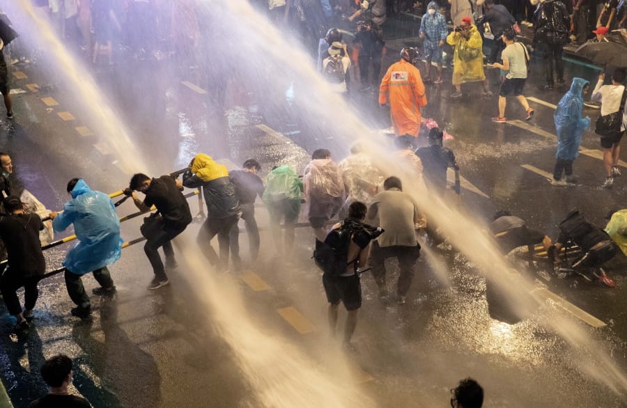 Pro democracy demonstrators face water canons as police try to disperse them from their protest venue in Bangkok, Thailand, Friday, Oct. 16, 2020. Thailand prime minister has rejected calls for his resignation as his government steps up efforts to stop student-led protesters from rallying in the capital for a second day in defiance of a strict state of emergency.