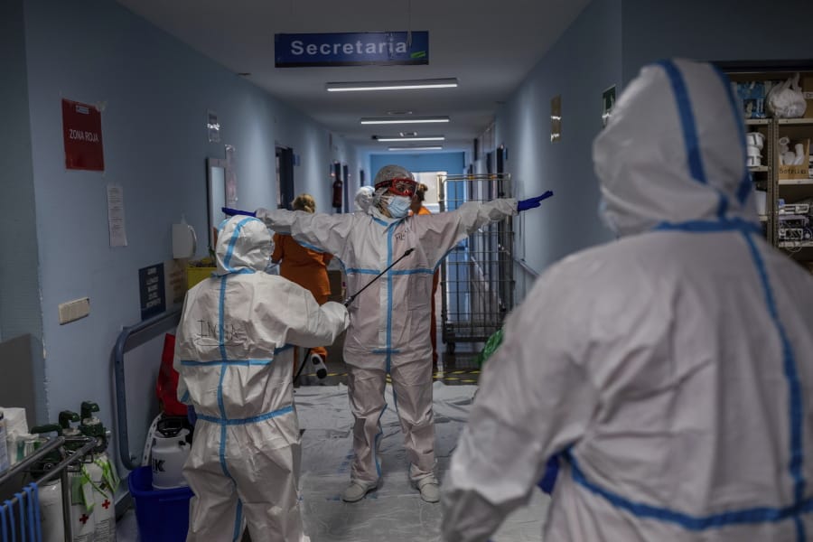 A medical team member is disinfected before leaving the COVID-19 ward at the Severo Ochoa hospital in Leganes, outskirts of Madrid, Spain, Friday, Oct. 9, 2020. At the peak of the first wave, ICU wards were given over to haste, desperation and even cluelessness about what to do. Now, a well-oiled machinery saves some lives and loses others to coronavirus, but without the doomsday atmosphere of March and April.