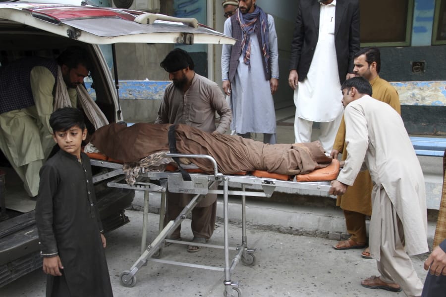 Afghan carry body of a woman who was killed in a stampede the city of Jalalabad east of Kabul, Afghanistan, Wednesday, Oct. 21, 2020. At least 11 women were trampled to death when a stampede broke out Wednesday among thousands of Afghans waiting in a soccer stadium to get visas to Pakistan, officials said.