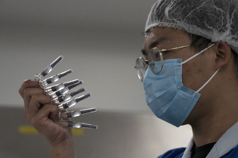 In this Sept. 24, 2020, file photo, an employee manually inspects syringes of the SARS CoV-2 Vaccine for COVID-19 produced by Sinovac at its factory in Beijing. China is rapidly increasing the number of people receiving its experimental coronavirus vaccines, with a city offering one to the general public and a biotech company providing another free to students going abroad.