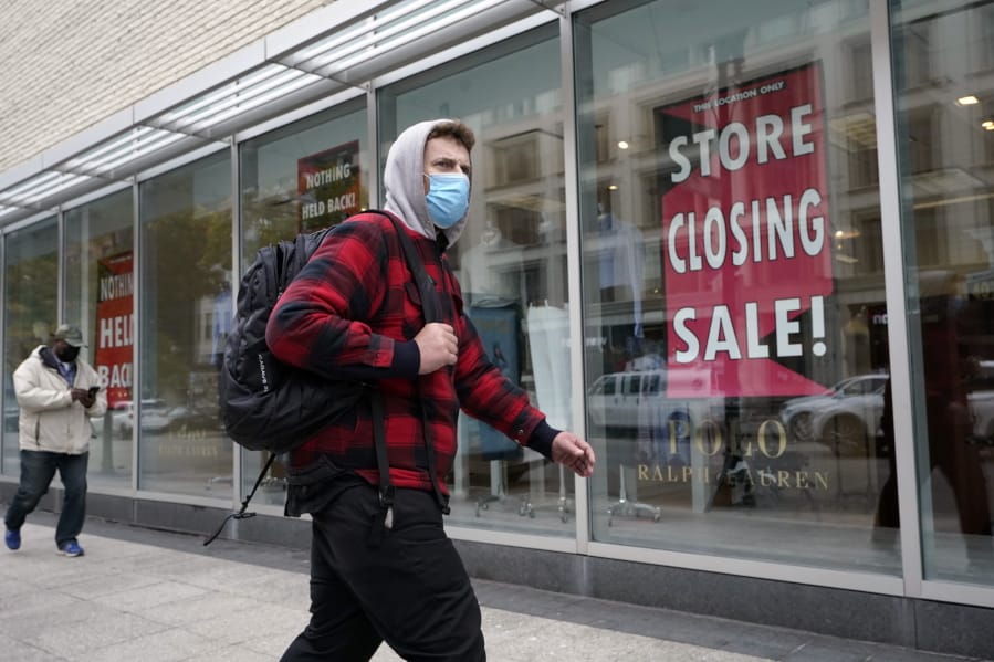 A passer-by walks past a store closing sign, right, in the window of a department store, Tuesday, Oct. 27, 2020, in Boston.  Americans may feel whiplashed by a report Thursday, Oct. 29,  on the economy&#039;s growth this summer, when an explosive rebound followed an epic collapse.