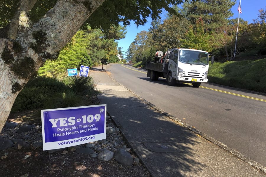 A truck drives past a sign supporting a ballot measure that would legalize controlled, therapeutic use of psilocybin mushrooms, Friday, Oct. 9, 2020 in Salem, Ore. War veterans with PTSD, terminally ill patients and others suffering from anxiety are backing the ballot measure.