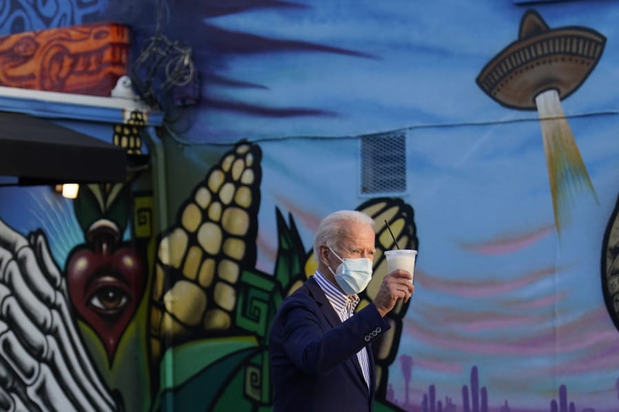 Democratic presidential candidate former Vice President Joe Biden holds a beverage as he leaves Barrio Cafe in Phoenix, Thursday, Oct. 8, 2020, during their small business bus tour.