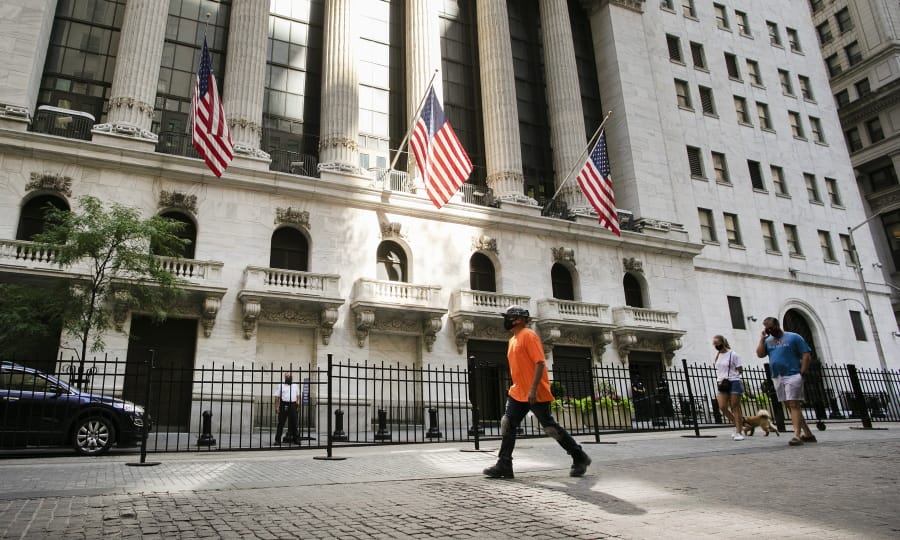 FILE- In this July 21, 2020 file photo, people walk by the New York Stock Exchange.  Stocks are falling in early trading on Friday, Oct. 30,  as Wall Street closes out a punishing week and its first back-to-back monthly loss since March, when worries about the pandemic were first peaking.