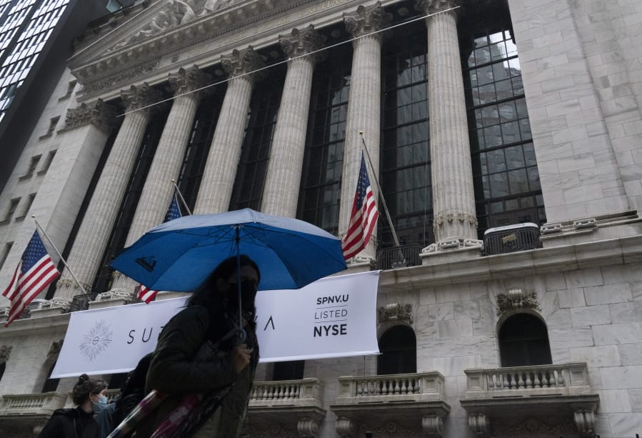 A woman with an umbrella passes the New York Stock Exchange, Monday, Oct. 26, 2020. U.S. stocks are drifting Tuesday, Oct. 27, 2020, as momentum slows a day after Wall Street slumped to its worst loss in a month on worries about rising virus counts and Washington&#039;s inability to deliver more aid to the economy.