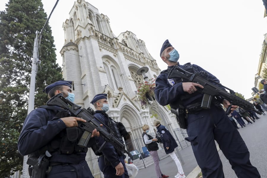 French police officers stand near Notre Dame church in Nice, southern France, Thursday, Oct. 29, 2020. French President Emmanuel Macron has announced that he will more than double number of soldiers deployed to protect against attacks to 7,000 after three people were killed at a church Thursday.