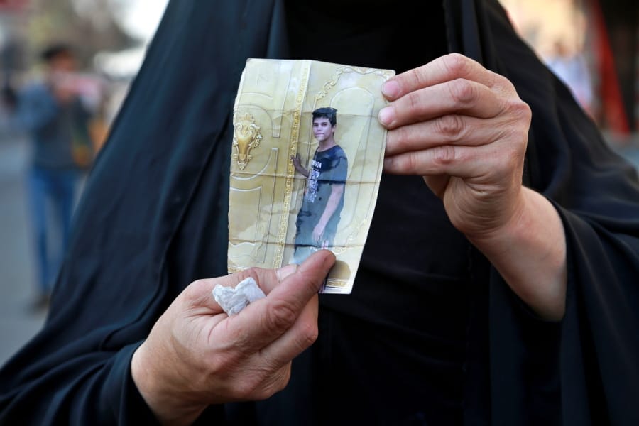 A woman holds a picture of her a missing son during anti-government protest in Baghdad, Iraq, Sunday, Feb. 23, 2020. There are 25 activists still missing since the protests erupted on Oct. 1, 2019, according to the semi-official Iraqi High Commission for Human Rights. No group has claimed responsibility but activists have blamed the militias.