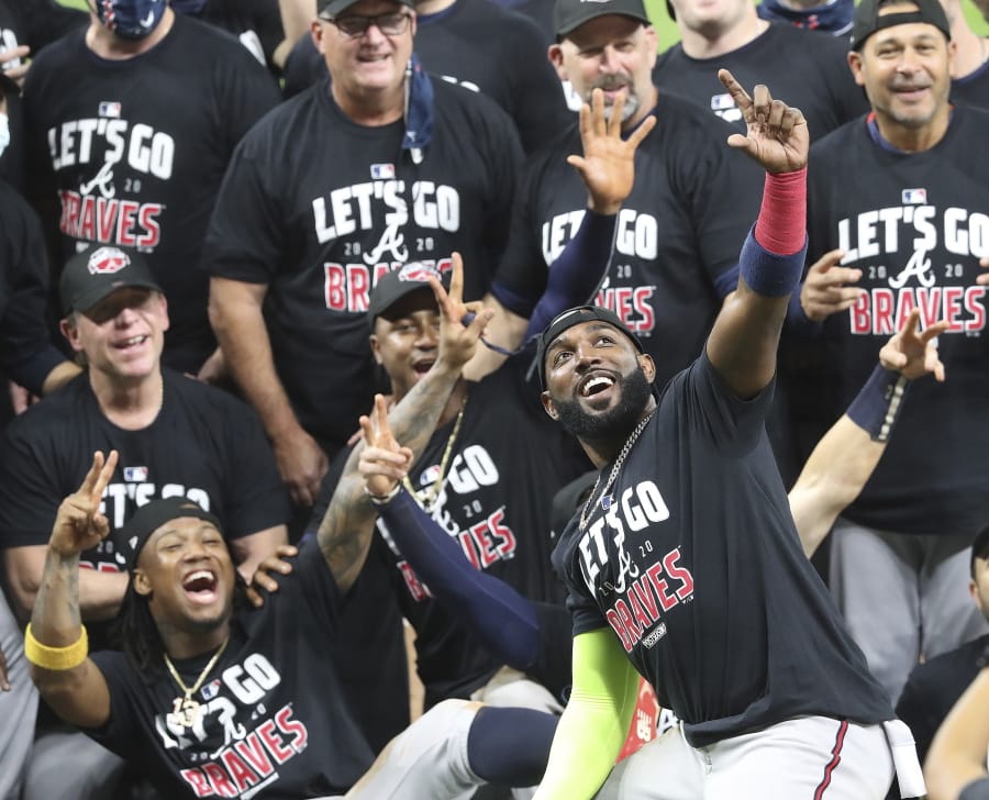 Atlanta Braves&#039; Marcell Ozuna, front, pretends to take a selfie as he celebrates with teammates after they defeated the Miami Marlins in Game 3 of a baseball National League Division Series, Thursday, Oct.