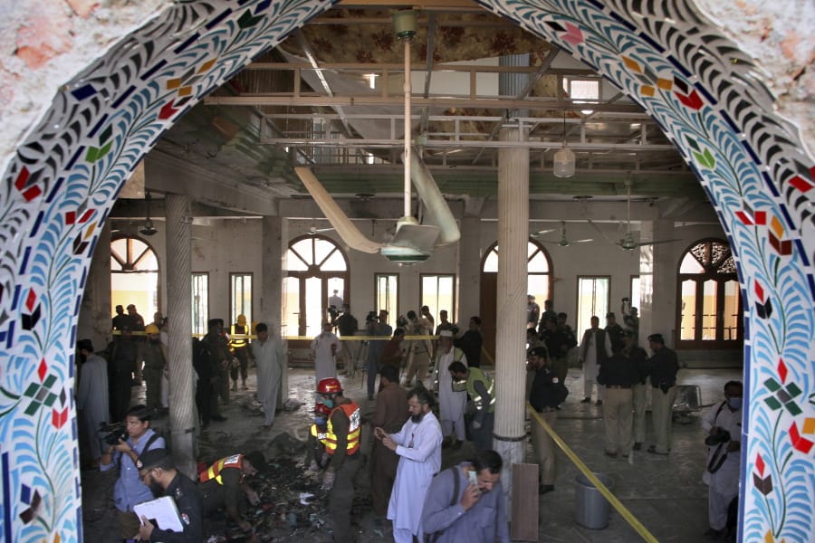 Pakistani rescue workers and police officers examine the site of a bomb explosion in an Islamic seminary, in Peshawar, Pakistan, Tuesday, Oct. 27, 2020. A powerful bomb blast ripped through the Islamic seminary on the outskirts of the northwest Pakistani city of Peshawar on Tuesday morning, killing some students and wounding dozens others, police and a hospital spokesman said.
