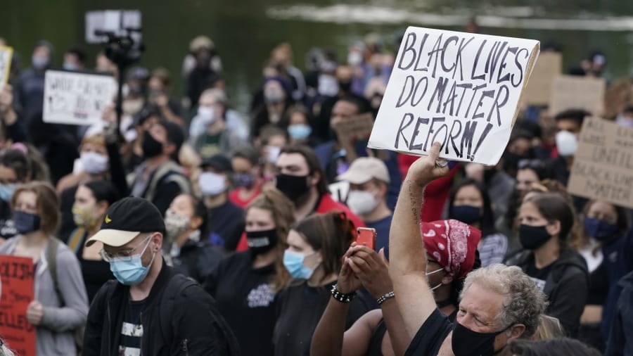 A man holds up a sign during a protest, Tuesday, Sept. 29, 2020, in Cleveland. Racism trips up Black police candidates at the very beginning of the application process and as they seek later promotion, complicating efforts to make law enforcement agencies more diverse, say numerous experts and Black police associations and officers.