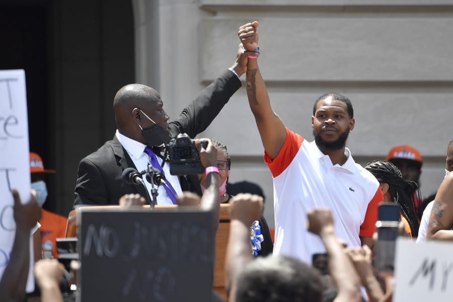 Attorney Benjamin Crump, left, holds up the hand of Kenneth Walker during a rally on the steps of the Kentucky State Capitol in Frankfort, Ky., Thursday, June 25, 2020. Walker was the boyfriend of Breonna Taylor who was killed by officers of the Louisville Metro Police Department following the execution of a no knock warrant on her apartment on March 13, 2020. (AP Photo/Timothy D.