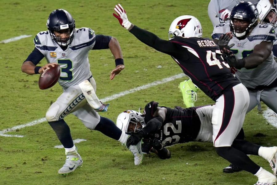 Seattle Seahawks quarterback Russell Wilson (3) escapes the reach of Arizona Cardinals strong safety Budda Baker (32) as outside linebacker Haason Reddick (43) pursues during the second half of an NFL football game, Sunday, Oct. 25, 2020, in Glendale, Ariz. (AP Photo/Ross D.