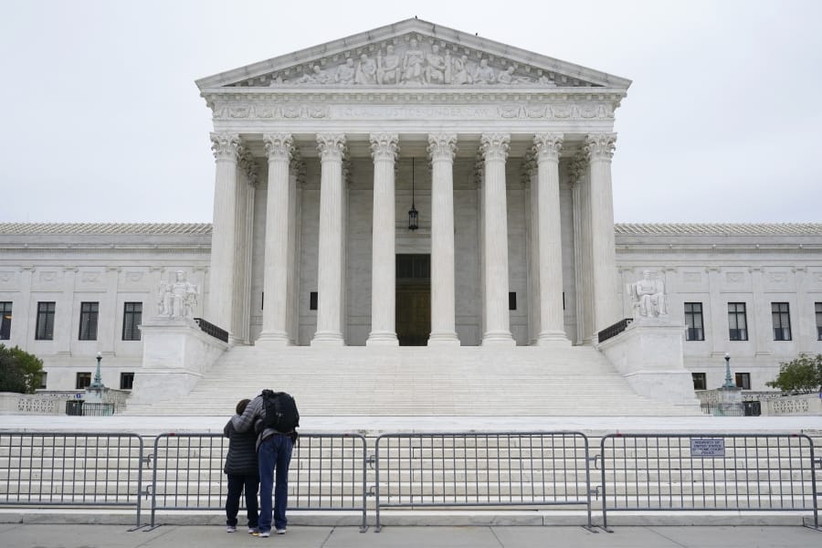 A woman and man pray outside the Supreme Court on Capitol Hill in Washington, Tuesday, Oct. 27, 2020, the day after the Senate confirmed Amy Coney Barrett to become a Supreme Court Justice.