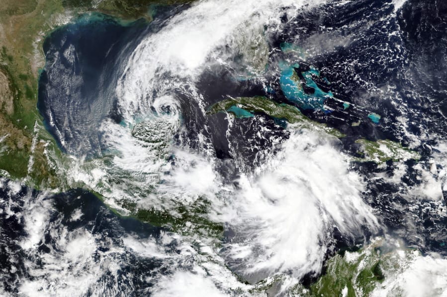 This Monday, Oct. 5, 2020, satellite image released by NASA Worldview, Earth Observing System Data and Information System (EOSDIS) shows Tropical Storm Gamma, left, which soaked part of Mexico over the weekend and a strengthening Hurricane Delta, lower right, which is on a course to pass by the Cayman Islands early Tuesday.