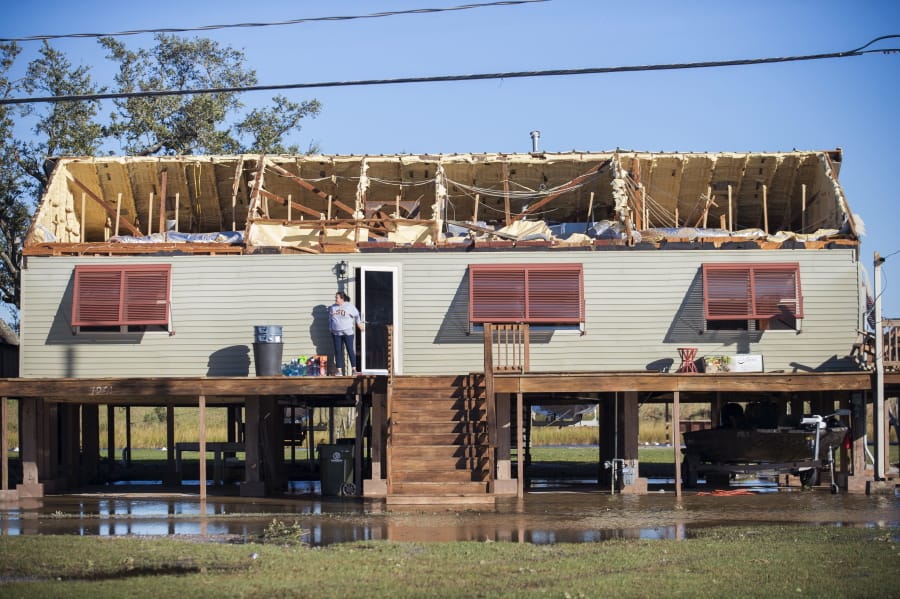 A woman walks out of a house where the roof was torn away during Hurricane Zeta, as people begin the process of cleaning and rebuilding in Chauvin, La., Thursday, Oct. 29, 2020.