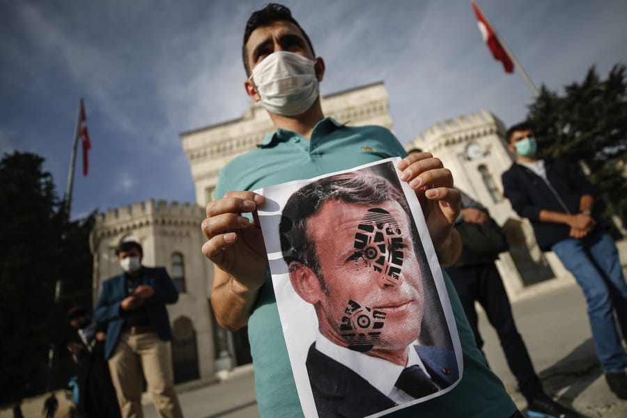 A youth holds a photograph of France&#039;s President Emmanuel Macron, stamped with a shoe mark, during a protest against France in Istanbul, Sunday, Oct. 25, 2020. Turkish President Recep Tayyip Erdogan on Sunday challenged the United States to impose sanctions against his country while also launching a second attack on French President Emmanuel Macron. Speaking a day after he suggested Macron needed mental health treatment because of his attitude to Islam and Muslims, which prompted France to recall its ambassador to Ankara, Erdogan took aim at foreign critics.