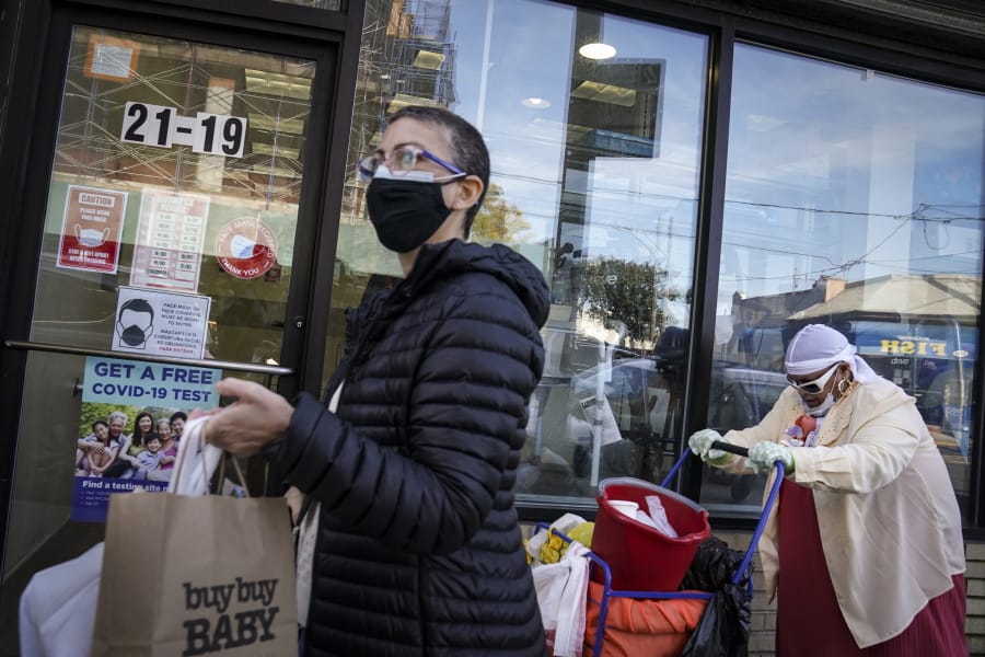 Pedestrians in protective masks pass a storefront on Thursday, Oct. 15, 2020, as restrictions on operations are imposed due to an increase in COVID-19 infections in the Far Rockaway neighborhood of the borough of Queens in New York. After shutdowns swept entire nations during the first surge of the coronavirus earlier this year, some countries and U.S. states are trying more targeted measures as cases rise again around the world. New York&#039;s new round of shutdowns zeroes in on individual neighborhoods, closing schools and businesses in hot spots measuring just a few square miles.
