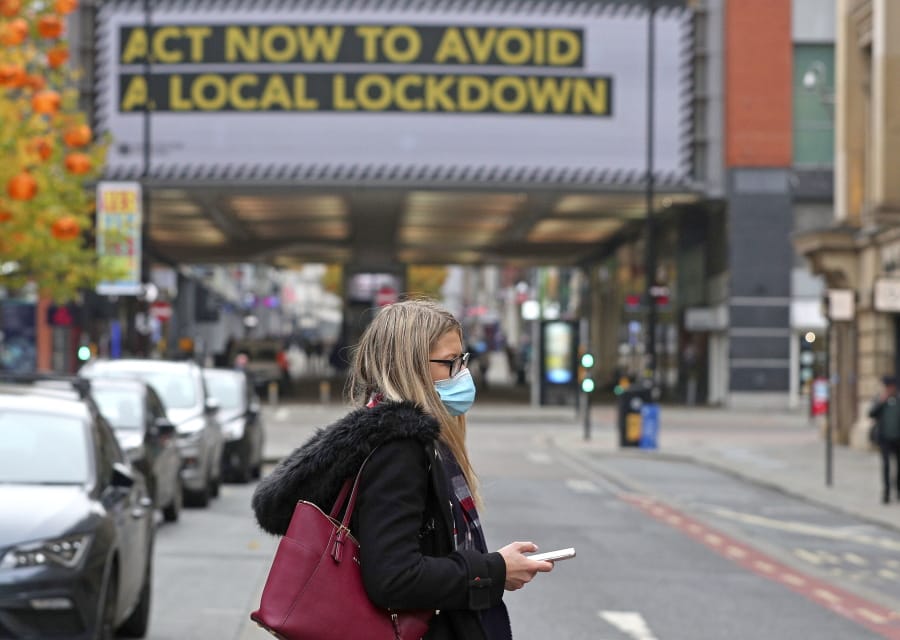 A woman wearing a face mask walks in Manchester, England, Monday, Oct. 19, 2020. Britain&#039;s government says discussions about implementing stricter restrictions in Greater Manchester must be completed Monday because the public health threat caused by rising COVID-19 infections is serious and getting worse.