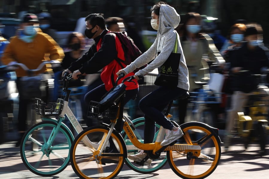 People wearing face masks to help curb the spread of the coronavirus ride bicycle during the morning rush hour in Beijing, Monday, Oct. 12, 2020. Even as China has largely controlled the outbreak, the coronavirus is still surging across the globe with ever rising death toll.