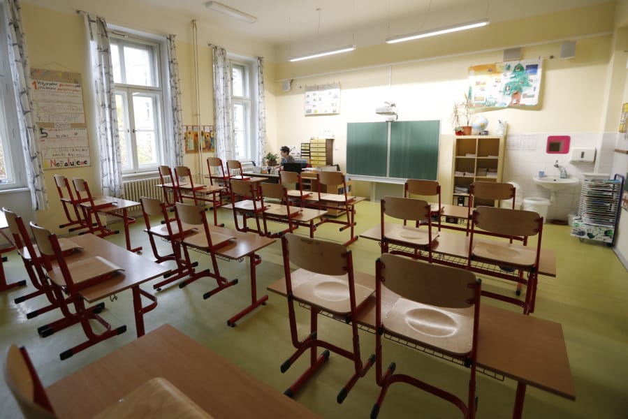 A teacher sits in an empty classroom and prepares materials for children at a closed school in Prague, Czech Republic, Wednesday, Oct. 14, 2020. Amid widespread efforts to curb the new wave of coronavirus infections in one of the hardest hit European countries, the Czech Republic closed again all its schools on Wednesday.