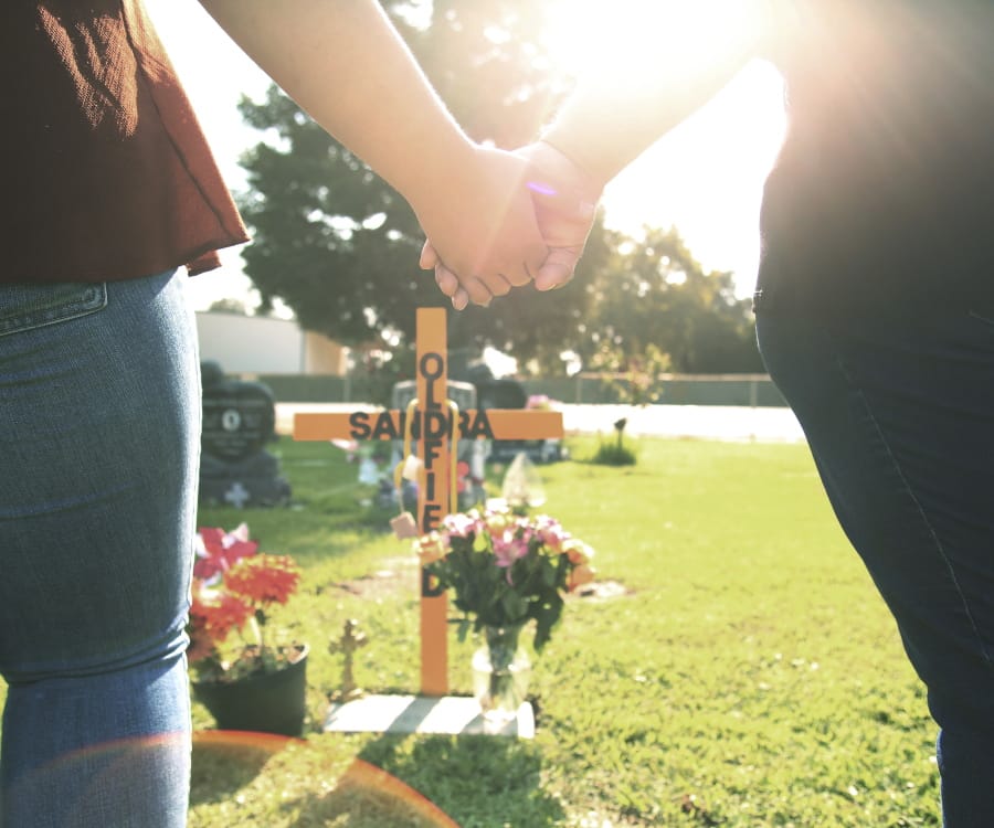 Lori Gonzalez, right and her daughter, Mariah Rodriguez, hold hands at the temporary grave marker of her sister and Kaiser Permanente Fresno Medical Center nurse, Sandra Oldfield, at the Sanger Cemetery in Sanger, Calif., Saturday, Aug. 29, 2020. Oldfield became ill and then died after being exposed to a patient who had COVID-19. Workers at the hospital said they did not have the proper personal protective equipment.
