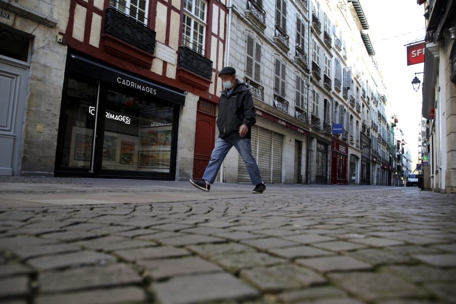 A man walks in an empty street during a nationwide confinement to counter the Covid-19, in Bayonne, southwestern France Friday, Oct. 30, 2020 . France re-imposed a monthlong nationwide lockdown Friday aimed at slowing the spread of the virus, closing all non-essential business and forbidding people from going beyond one kilometer from their homes except to go to school or a few other essential reasons.