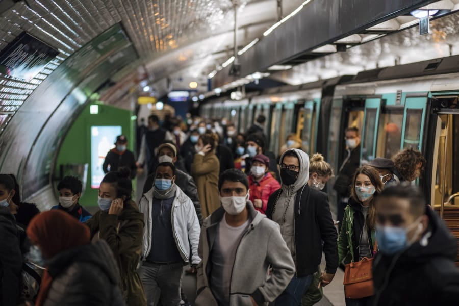 Commuters wearing face masks walk on the platform, of a Paris subway, Sunday Oct.25, 2020. A curfew intended to curb the spiraling spread of the coronavirus, has been imposed in many regions of France including Paris and its suburbs.