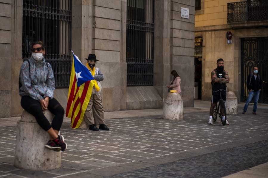 A man holding an &quot;estelada&quot; or independence flag waits for a protest to condemn a police raid on Catalan separatists in Barcelona, Spain, Wednesday, Oct. 28, 2020. Spanish officials say that police have arrested 21 individuals with links to the Catalan separatist movement on suspicion of corruption and promoting public disorder.