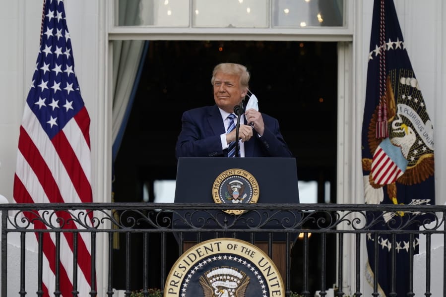 President Donald Trump removes his face mask to speak from the Blue Room Balcony of the White House to a crowd of supporters, Saturday, Oct. 10, 2020, in Washington.
